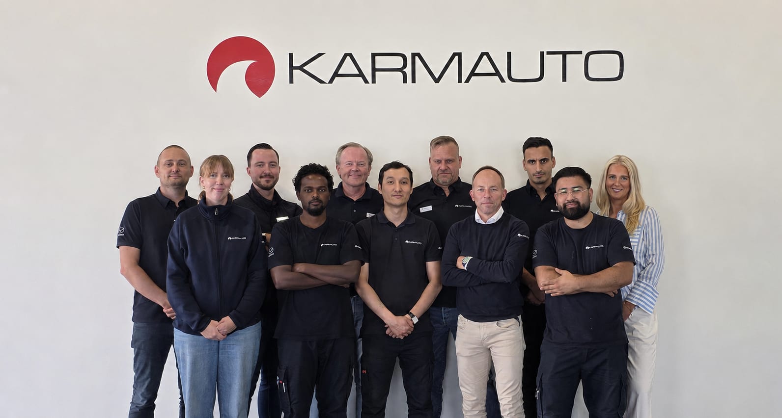 Teamet på Karmauto står samlat framför Karmautos logotyp